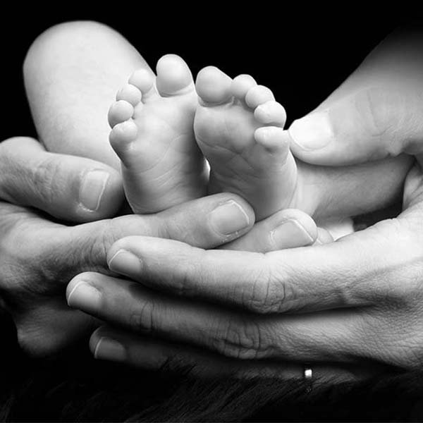 Pies del bebé en manos de su papá